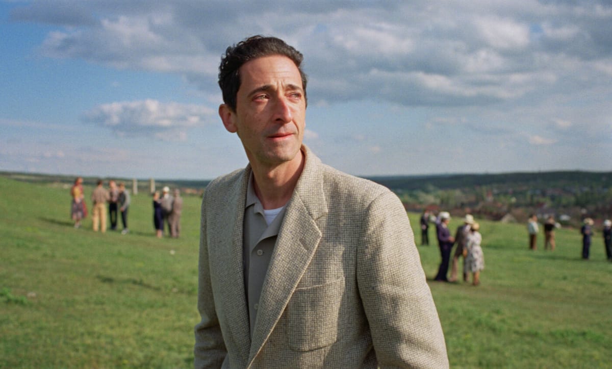 Adrien Brody on a hillside in a still from the film The Brutalist
