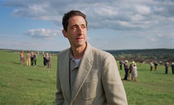 Adrien Brody on a hillside in a still from the film The Brutalist
